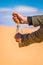 Man pouring sand to the bottle in desert with sandstone and granite rock Wadi Rum in Jordan