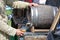 A man pours beer into a glass with a wooden barrel