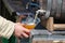 A man pours beer into a glass with a wooden barrel