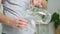 Man pours cold water into glass. Close-up of male hands pouring water from a jug into glass tumbler.