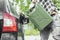 Man pours gasoline from a canister directly into the tank of a car. Green Jerrycan full of gas. Fuel shortage while travelling