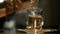 Man pours green tea into a glass cup from the brewer. Close-up.