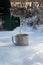 A man pours hot tea from a thermos into a mug on the river in winter.