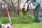 Man pours out of the trimmed grass under a tree to fertilize the soil