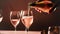 A man pours pink champagne into elegant glass goblets. Restaurant, holiday, party. AI generated