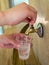 Man pours water on the mineral springs in a plastic cup