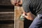 A man with a powerful tool with an angle grinder cleans the wood of the fence