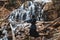 Man practicing kendo with bamboo sword on waterfall, rocks and forest background. Place for text or advertising