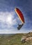 Man practicing paragliding at the moment of starting the flight with the sun shining in the background