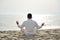 Man practicing yoga meditation on the beach at sunset- healthy lifestyle concept