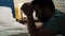 Man is praying. Bearded man sits on floor in bedroom by bed, holds rosary with crucifix in his hands and says prayer