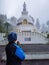Man praying at buddhist shanti stupa covered with misty fog at morning from different angle