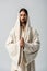 Man with praying hands and jesus robe with hood standing isolated on grey