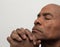 Man praying to god with hands together Caribbean man praying stock photo