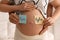 Man and pregnant woman with different baby names on belly indoors, closeup