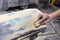 A man prepares a car body element for painting after an accident with the help of grinding abrasive paper in a car repair shop.