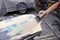 A man prepares a car body element for painting after an accident with the help of grinding abrasive paper in a car repair shop.