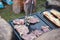 Man prepares a juicy pork neck with basil and barbecue spices and a baguette with tomato cheese and ham on a hot granite slab.