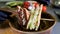 Man prepares lunch, serves grilled bread sandwich snack on top of wooden cutting board, with side of green salad