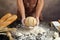 Man preparing buns at table in bakery, Man sprinkling flour over