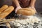 Man preparing buns at table in bakery, Man sprinkling flour over