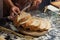 Man preparing buns at table in bakery, Man sprinkling flour over