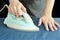 man pressing automatic electric iron to shirt on ironing board