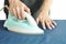 Man pressing blue automatic electric iron to shirt on ironing board