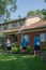 Man pressure washes the siding on his house with his two teenage sons watching. The man is spraying water on the top floor. The