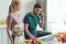 man pretending talking on cucumber at table with laptop and girlfriend