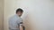 Man priming the wall with a brush. Repair of the interior. Young male decorator painting a wall in the empty room