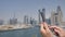A man prints a message on the phone in the background of the panorama of Dubai. Hand close-up.