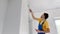 A man professional construction worker paint the wall using a roller painter. Slowmotion shot