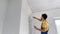 A man professional construction worker paint the wall using a roller painter. Slowmotion shot