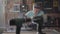 The man in protection glasses cutting a wooden board with a small circular saw on the table in the workshop. Furniture