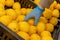 A man in protective blue gloves takes a lemon. Close-up, no face visible. Buying grocery food during a pandemic