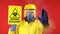 A man in a protective chemical mask and a protective yellow suit with a banner in his hand with the words biohazard