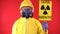 A man in a protective chemical suit, in a protective mask with the poster "Caution radiation". Radiation hazard concept
