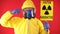 A man in a protective chemical suit, in a protective mask with the poster "Caution radiation" and twists his finger at