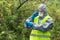 A man in protective gloves and a mask looks at the device showing the level of radiation on the street and transmits information