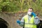A man in protective gloves and a mask makes a quick analysis of water from the river for pollution and transmits information by