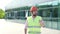 Man in protective helmet and vest makes report standing on construction site.