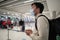 Man in protective mask with phone at airport departure check-in desk for baggage drop-off at terminal and check-in for