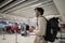 Man in protective mask with phone at airport departure check-in desk for baggage drop-off at terminal and check-in for