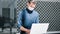 Man in a protective mask spraying a bactericidal spray on the surface of a laptop.