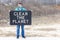 Man in protective medical face mask with a black piece of fabric with text clean the planet