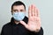 Man in protective medical mask on face show stop viruse by hand gesture