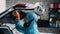 A man in a protective suit cleans and cleans the luggage compartment of the car.