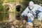 A man in a protective suit does an express test-tube test on the river bank