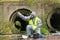 A man in a protective suit and mask from bacteria and viruses drops reagent from a pipette into the river water during an express